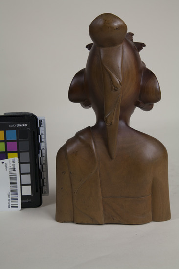 Hearst Museum object 5 of 8 titled Bust, accession number TEMP 2018.998, described as carved wooden female bust (head) signed Sinpar. 9.5"h with long hair pinned up; she wears a headdress, earrings, and strapless garment with cloth over her left shoulder; bust stops at waist and elbows; on bottom is carved "Io Bc. Kp SIMPAR, SANUR., BALI."; "6250" written in black pen on bottom.