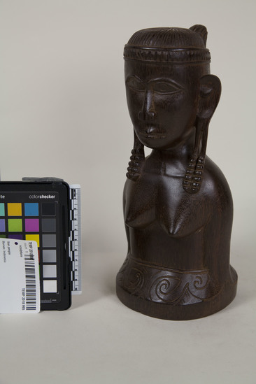 Hearst Museum object titled Sculpture, accession number TEMP 2018.995, described as Eban female bust 10"h figure stops at waist, with bare breasts and a headband; she has long hair and extended earlobes with decorations; base around waist has incised designs