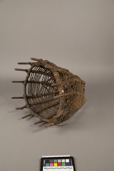 Hearst Museum object titled Basket, accession number 5-13320, described as In-Jel., Kenya, Gob Ore, Rendille. Summer, 1977. 5-13320, acc no. 3332. File code: 1.5 Collector: Jean Colvin. Donor: Jean Colvin. Materials, techniques: Branches of Ha-lah tree- tied with camel hide straps and bottom skin covering-cut into strips which are softened in water and soil basket for storing small things in house Context of use: Hangs on women's side of house Description: Basket; open lattice of wood sticks bent in U shape attached to circular piece at top; Series of twisted leather strips from top to bottom wound around each stick. Leather piece at bottom and one side H=38 cm D=34cm. References: for additional information see field sheets in acc. env.