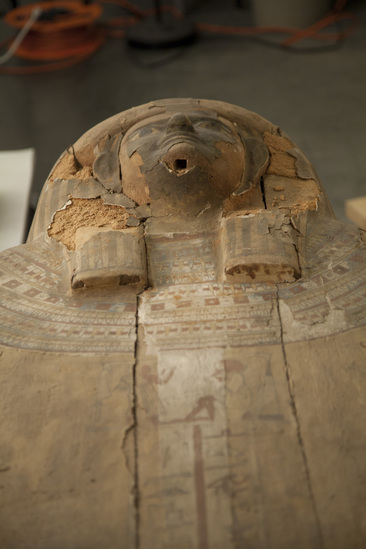 Hearst Museum object 153 of 167 titled Coffin, accession number 6-19912, described as Wooden anthropoid coffin. Inscription running down center of lid. Determined by Kea Johnston to probably be the outer coffin of Iwefaa (6-19928, 12-11039). According to Kea Johnston, "This coffin belonged to a man named Iwefaa, whose name is inserted in the middle of the spells written in the two columns on the front. This coffin is likely the outer coffin for PAHMA 6-19928 based on the similarity of the owner's name, unusual costume, and the paleography of the inscription. Both coffins were purchased on the antiquities market by George Reisner for Phoebe A Hearst. However, stylistically, they are very similar to a set of coffins known to have come from the site of Akhmim, which was excavated in the 1880s by Gaston Maspero, and which has heavily looted for the antiquities market during this decade." "The pectoral vignette between the text and the collar shows the deceased standing before squatting baboon and is the source of our logo. The hieroglyph for 'sky' is above their heads, and the side borders are formed by a pyramid and the symbol for the West.