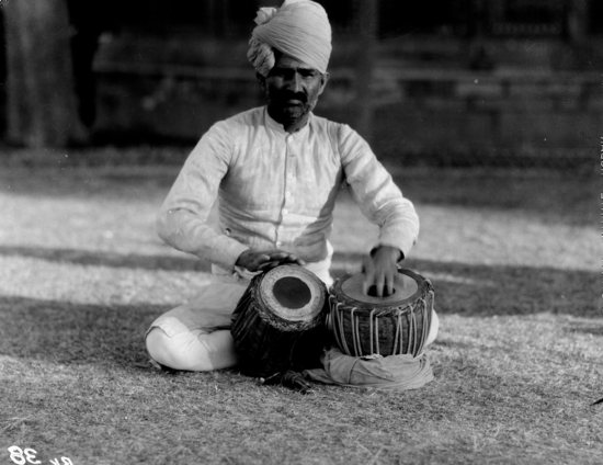 Hearst Museum object titled Black-and-white negative, accession number 15-30388, described as 4 X 5" Black and white negative of a man with two drums or baskets.  Hoefler's original description: "Bikaner State Northern India. Indian man, seated, with two drums.