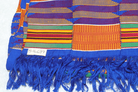 Hearst Museum object 3 of 4 titled Shawl, accession number 5-16697, described as Kente cloth shawl; 5 narrow strips sewn together to form a shawl with fringes on each end (blue). colors include golden yellow, green, dark red, royal blue, black and white. alternating patterns of basket like design, colored stripes and solid blue sections.