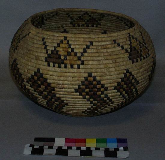 Hearst Museum object titled Basket, accession number 2-18623, described as Coiled, wide mouth, globular.  Light cream, brown, yellow, and black.  Flat bottom; 6 pairs of checkered zigzag designs connected at the base; 6 triangles above zigzag pattern with black "arms" emanating from each side opposite base.