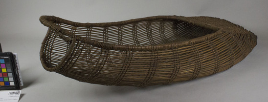 Hearst Museum object 3 of 3 titled Cradle, accession number 1-164484, described as Twined basketry.  Tag "Klamath R. Tribes Att.". Per Ralph Shanks:  Twined openwork baby basket.  The warp material is probably willow, possibly hazel.  The wefts are of uncertain material.  At the foot there is plain twining, spaced closer than the rest of the basket.  The rim is covered,  reinforced with rods.  Starting at the foot there are sets of three paired weft rows all the way to the handle.  The basket has alternating slants of weft twists, often switching by weft row.  The basket is from Northwestern California.