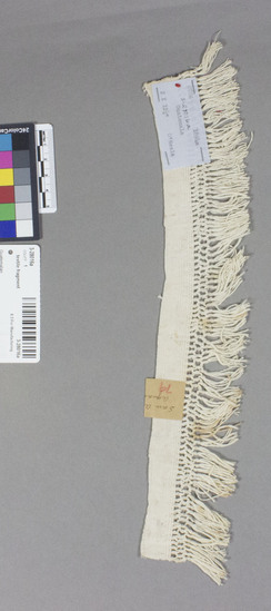 Hearst Museum object titled Textile fragment, accession number 3-28016a, described as White cotton textile fragment. 2-3 basket weave, macrame fringed. 2 X 12 1/4 inches.