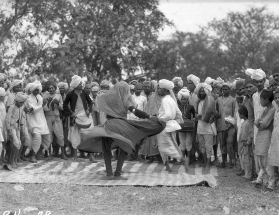 Hearst Museum object titled Black-and-white negative, accession number 15-30501, described as 4 x 5" Negative.  Bhopal State, Central India. Village dancer surrounded by a crowd. Hoefler's original description: "Bhopal State, Central India. A village dancer in action. After the tiger hunts the villagers paid a visit to the Nawab's camp in order to celebrate the killing of these destructive cats. There was great rivalry between the villages, each one trying to out-do the other in the varieties of the dances and by the amount of wild rhythm emitted from the respective orchestras.