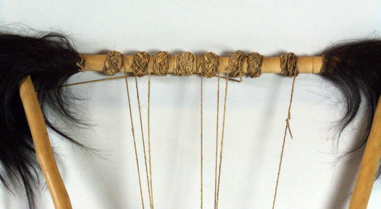 Hearst Museum object 8 of 9 titled Lyre, accession number 5-6641, described as bowl lyre; traditional lyre shape; top and side pieces straight solid cylindrical sticks; wood sound box with sound table of reptile skin; back covered with goat hide; skin lacing; 1 sound hole; 8 twisted gut strings.