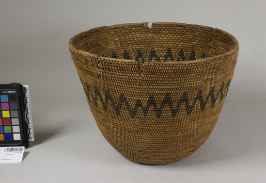 Hearst Museum object 2 of 2 titled Basket, accession number 1-211528, described as Coiled; conical in form with a flat bottom. Decoration: black zigzag band. Basket is damaged at the rim in several places. 3-rod coiling with stitches split on interior face; herringbone border stitch a rim.