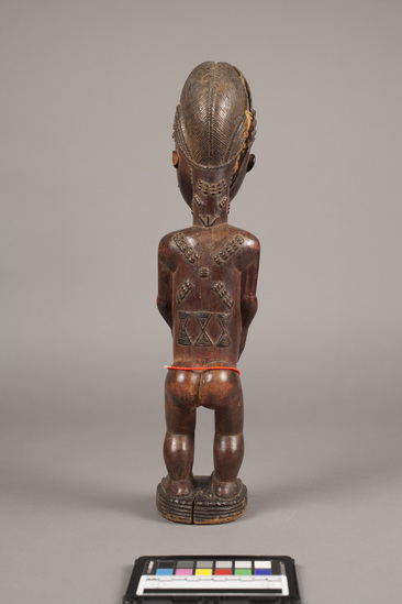 Hearst Museum object 6 of 7 titled Figurine, female, accession number 5-3182, described as carved wooden figure; standing female with hands clasped around protruding umbilicum; string of red beads around thighs;