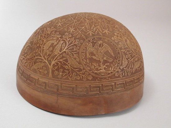 Hearst Museum object titled Gourd bowl, accession number 3-29443, described as Bowl, hemispherical, of tree gourd shell, incised cameo-like designs of birds, trees and circular insets, one of which has the inscription "Republica Mexicana" over an eagle holding a snake; 22 cm diam., 11 cm depth