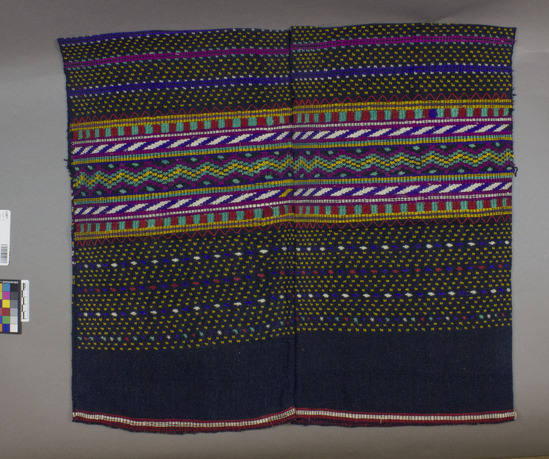 Hearst Museum object titled Huipil, accession number 3-28077, described as [ cat card Description: Blouse two pieces sewn together Materials:cotton, silk Technique: Plain weave, brocaded, weft striped Colors: dark blue ground, varicolored designs Dimensions: 24" x21" Remarks:   Geometric motives    ]