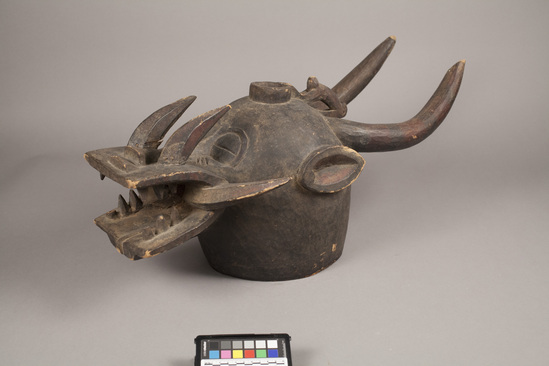 Hearst Museum object titled Helmet mask, accession number 5-5342, described as Carved, wooden, “fire spitter, helmet mask. Dark stained wood with carved monkey on top. L = 71.0 cm