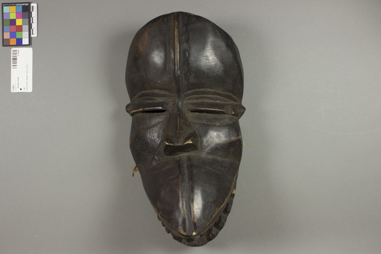 Hearst Museum object titled Wooden mask, accession number 5-14363, described as Mask; wood dance mask, zoomorphic; hinged lower jaw, carved teeth; eye slits; dark-stained wood; lacing holes. Dance mask, said to be Dan, but closely resembles 5-5466, which is Kran. Height at back 34.5 cm.