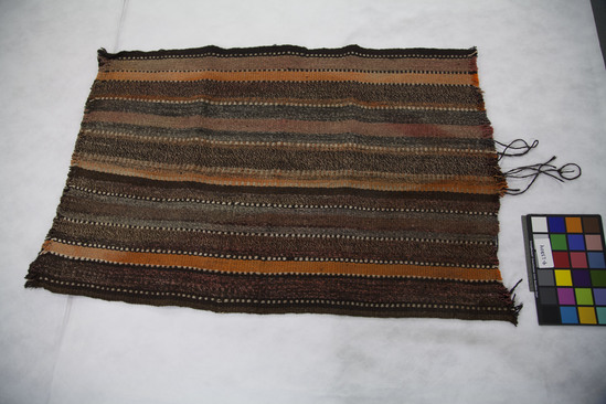 Hearst Museum object titled Tent wall or shelter wall, accession number 9-23804, described as Wall for tent or shelter, hidim, is a piece of a much longer strip. It is in natural colors - gray, brown, and white - with orange and red (faded totally) over dye in plain weave in vertical stripe and dot/horizontal stripe pattern. It was cut off a large piece because I didn't have space to bring the whole piece. Made for self and used as a windbreak. Might have been used for human shelter before their houses were built, but more likely used for goat shelters. Z-ply, commercial dye used but unsure, 10 thread count per inch. Warp-faced plain weave.