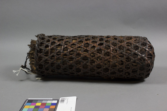 Hearst Museum object titled Basket, accession number 9-9143, described as basket; cylindrical shaped split bamboo caning filled with straw; twine handle; straw bundle for holding fish pick. Basket hung beside the fireplace for smoking river fish.