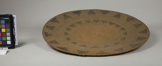 Hearst Museum object 3 of 3 titled Tray, accession number 1-28807, described as Basketry plaque, coiled with interlocking stitches on grass bundle foundation.  Decoration: two encircling bands of triangles in dark brown material (grass and brackenfern root). Basket has insect holes.