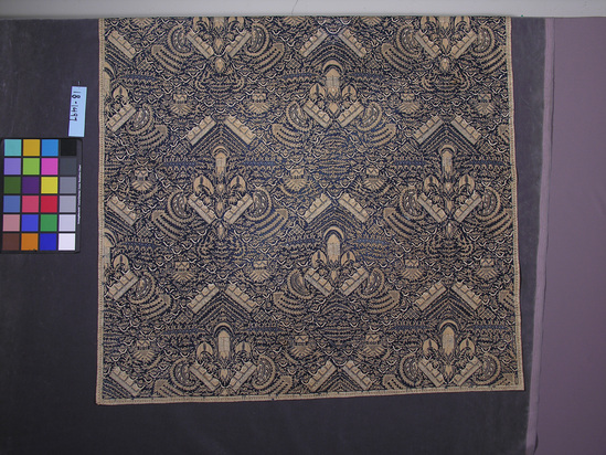 Hearst Museum object titled Headcloth, accession number 18-1497, described as Headcloth, cotton batik; indigo and beige; very abstracted Garuda motif with small geometric fillers; old stains. 108 x 108 cm.