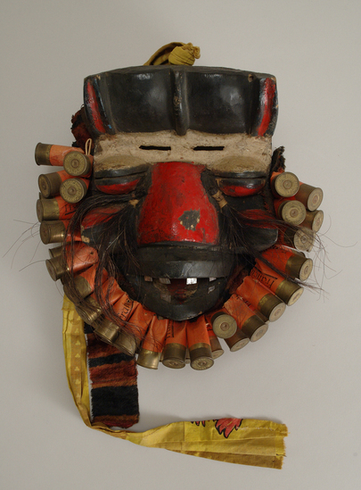 Hearst Museum object titled Face mask, accession number 5-3372, described as carved wooden face mask/ baboon (?); red nose and eyes; trimmed with empty shot-gun shells; hair attached; lined with cloth.