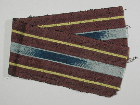 Hearst Museum object 1 of 2 titled Textile fragment, accession number 5-11336, described as textile sample (section of narrow band weaving): outside panels maroon with central yellow stripe, central ikat: blue and light blue flanked by light blue.