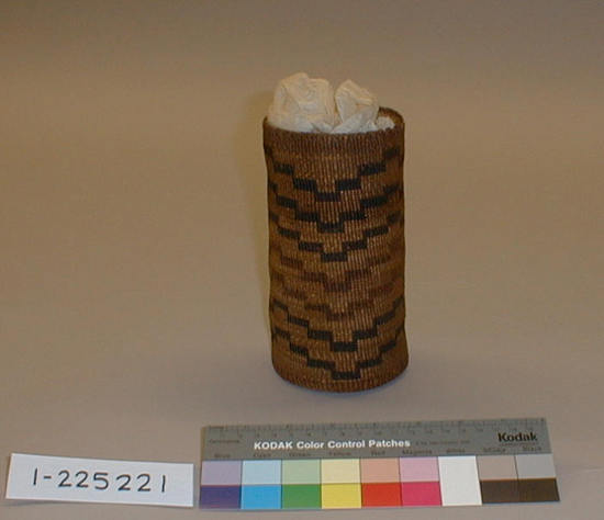 Hearst Museum object titled Basket, accession number 1-225221, described as Cylindrical, twined. 7 encircling design bands of stepped rectangles in red and dark brown material on tan ground. Novelty shape.