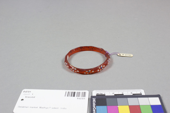 Hearst Museum object titled Bracelet, accession number 9-6701, described as Glass bangle bracelet; amber color; with white and blue painted design; diameter 2  1/4 inches.