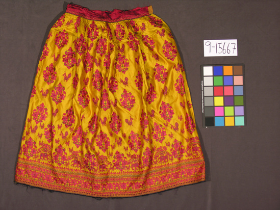 Hearst Museum object titled Skirt, accession number 9-15667, described as Skirt, "ghagra".  Silk.  Satin, embroidered.  Yellow ground, red, green, white and blue designs, red waistband.  Floral, elephant, bird motives.  33 inches long.