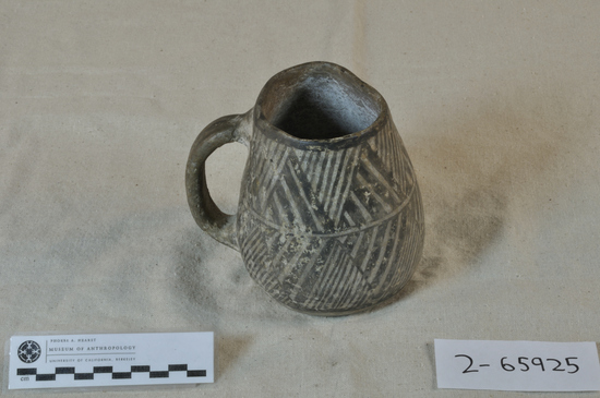 Hearst Museum object 2 of 3 titled Mug, accession number 2-65925, described as Mug with single handle; buff pottery; 2 bands of zigzags with diagonal fillers around the exterior.  The rim is chipped.  Pueblo III per Larry Dawson.