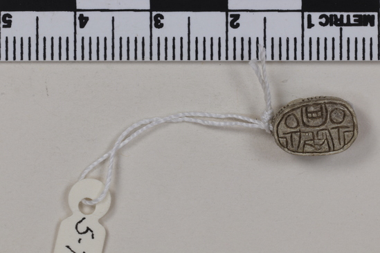 Hearst Museum object titled Scarab seal, accession number 5-7512, described as Seal: Scarab; stone with whitish glaze; protothrorax shown by notches; two lines crosshatched for legs; Reverse- shallow incised design; Height 5.3 mm. Length 1.1 cm. Width .8 cm.