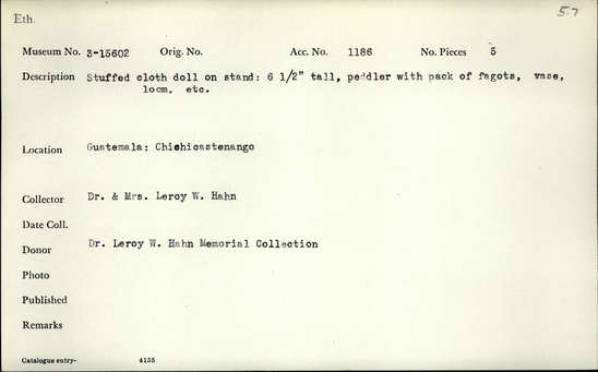 Documentation associated with Hearst Museum object titled Doll, accession number 3-15602, described as Stuffed cloth doll on stand: peddler with pack of fagots, vase, loom, etc. Height 6 1/2 inches.