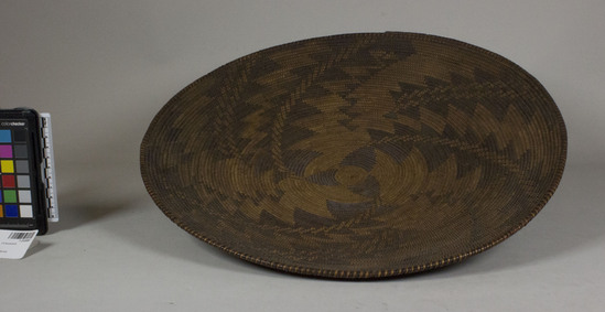 Hearst Museum object 2 of 2 titled Winnowing tray, accession number 1-232087, described as Coiled, shallow circular tray.  3-rod foundation. Peeled shoot foundation rods. Complex diagonal patterns in redbud material spiral out from center, alternate dark and light stitches on rim. Split peeled shoots and split redbud shoots.