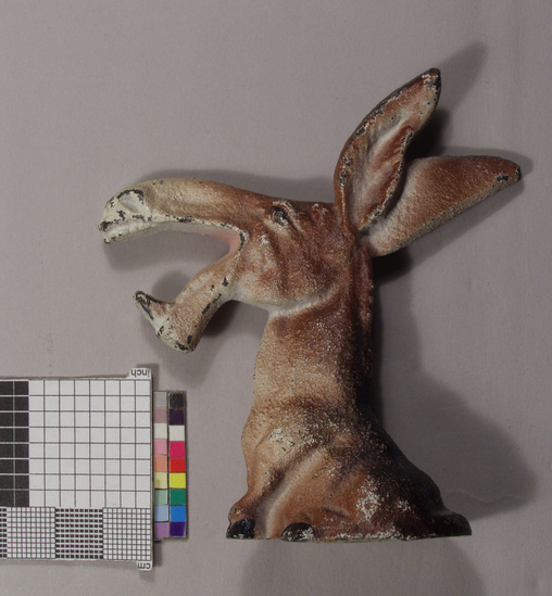 Hearst Museum object titled Bottle opener, accession number 2-69035, described as Bottle opener. Caplifter; zoomorphic; cast iron caricature of seated donkey with jaws as crown caplifter; 2-69034) painted gray; 2-69035) painted white and brown; each 9.0 cm long