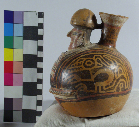 Hearst Museum object 10 of 13 titled Bottle, accession number 16-12114, described as Pottery bottle with flaring spout; effigy of a man with bag slung around neck; red and white slip and resist painted designs. Has been waxed