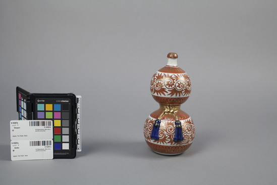 Hearst Museum object titled Sake bottle, accession number 9-16581a,b, described as Commercial sake bottle; Porcelain skewomorph of a bottle gourd.  Kiln mark under the glaze on the underside.