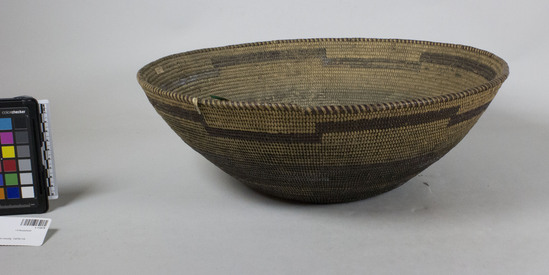 Hearst Museum object 2 of 2 titled Cooking basket, accession number 1-11879, described as Large flaring coiled basket.  Tag: "Yuki". Per Ralph Shanks:  Coiled flaring basket Yuki cooking bowl, with residue from food and wear from cooking.  The bottom 2/3rds of the exterior of the basket are blackened.  The basket has a twined start.  The coil foundation is two rods and splints of peeled shoots.  The wefts are peeled redbud with unpeeled redbud designs.  The design on the basket is three horizontal bands that drop down and go up at the same areas. There are no random rectangles. The rim is plain wrapped, with rim ticks.  The coil ending is cut off, with about three weft stiches missing.  The weft fag ends are primarily clipped or concealed.  The weft moving ends are primarily concealed.  The exterior has below 10% split stiches.  The interior of the basket has over 50% split stiches.  The basket has an exterior workface with a rightward work direction and a down to the right slant of weft twist.  The lack of random rectangles suggests some Wailaki influnce.