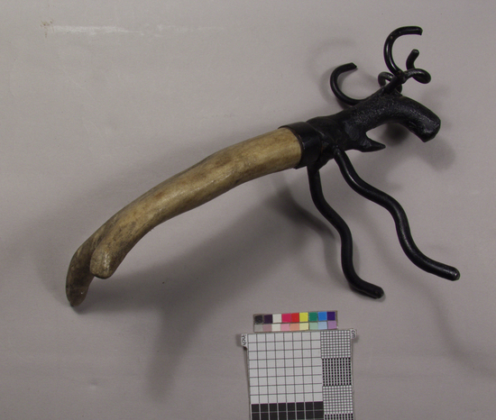 Hearst Museum object 1 of 2 titled Corkscrew, accession number 2-69023, described as Caplifter, zoomorphic; antler handle in shape of hind legs; wrought iron forelegs, head, and antlers in shape of deer, lower jaw serves as crown caplifter, painted black; 14.6 cm long.
