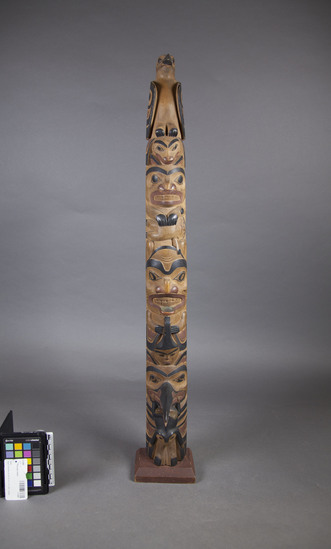 Hearst Museum object titled Totem pole model, accession number 2-14267, described as Bottom figures: frog and raven (with small copper in beak); yellow cedar painted red-brown and black.  (Identification of frog and raven and yellow cedar by Charles Brown (Tlingit Indian), June 1964)