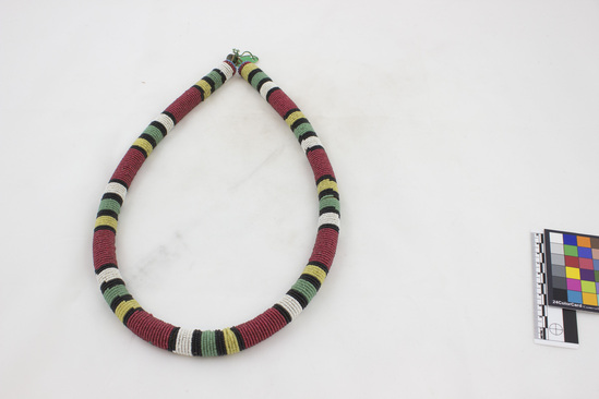 Hearst Museum object titled Beaded collar, accession number 5-7200, described as Beaded collar, cylindrical cross-section, 1 metal button for attachment; yellow, white, red, black beads in alternating pattern of bands. 74 cms length. Made of glass beads and string.