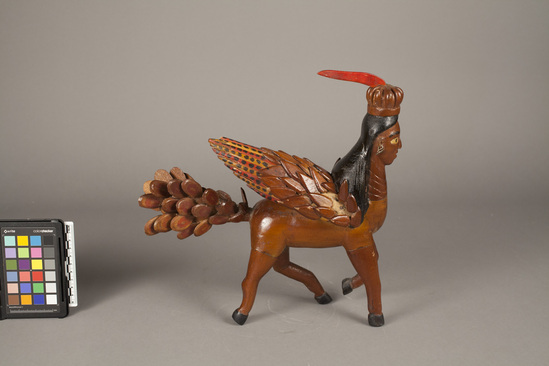 Hearst Museum object titled Figure, accession number 5-10184, described as Sculpture, depicts al-Buraq; wood; crowned centaur-like figure; red, black, yellow paint; varnished; single feathered winged back and feathered-like tail pieces missing.