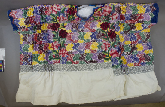 Hearst Museum object titled Huipil, accession number 3-29287, described as Huipil (blouse); white cotton with large embroidered flowers and geometric embroidery embellished with paired birds; blue velvet trim at neck and arm openings; Width across arms 89 cm.