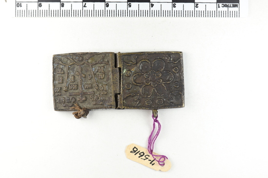 Hearst Museum object 4 of 4 titled Diptych, accession number 7-5618, described as Traveling icon, diptych; brass; scene on back of left half; Golgotha; inside left: Mother of God with Christ child being venerated by two saints; inside right: St. Nicholas flanked by Jesus on left; Mother of God on right; curvilinear design back of right half; width 6 cm., height 2.7 cm.