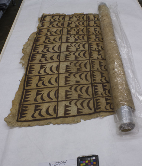 Hearst Museum object titled Tapa cloth, accession number 11-39404, described as Tapa; fringed; yellowed; dark brown pigments; design with fields divided into rectangles filled with rows of triangles and shapes; example of a type exchanged or given in a malanga (tour), i.e. a visiting of villages by a group and an exchange of gifts and shells, a meeting place of chiefs, talking chiefs, etc.; probably a wrapper (’afu) or a bedsheet (’afu loto)