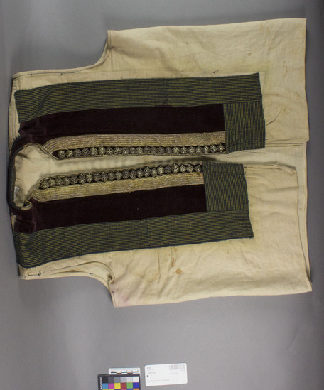 Hearst Museum object titled Waistcoat, accession number 7-5120, described as Woman's linen waistcoat (elek); green commercial cloth and velvet front; gold braid and metal openwork balls lining edge of front. Worn under sleeved vest 7-5121 and sleeveless coat, 7-5122, so that only narrow vertical band and buttons of front are seen. 7-5120-22 always worn as a single unit. Worn everyday but especially on Sunday and for festivals, and especially by younger women. Made by Terzija, professional tailors who make folk costumes. Worn by women at time of collection, 1964. 7-5119-5128 comprise a complete costume.