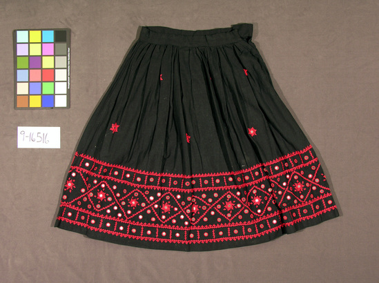 Hearst Museum object titled Skirt, accession number 9-16516, described as Skirt, mirrored; black cotton skirt with gathered waistband; red embroidered border on lower edge of skirt; mirrors appliqué to skirt with red thread.  Textile.  India.  Length 80 cm.