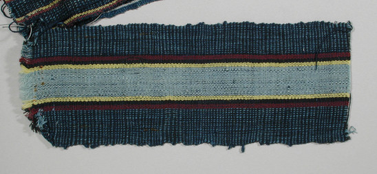 Hearst Museum object titled Textile fragment, accession number 5-11125, described as Textile sample (section of narrow band weaving): cotton; alternating black and pale blue threads on either side of central central stripe of light blue flanked by yellow, deep red, and black; deep blue ground.