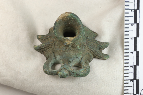 Hearst Museum object titled Bucket fragment, accession number 8-3236a,b, described as AB Bronze bucket handles and escutcheons; fragments; handles are 15.3 cm wide. Beardless mask, satyr mask, broken vessel
