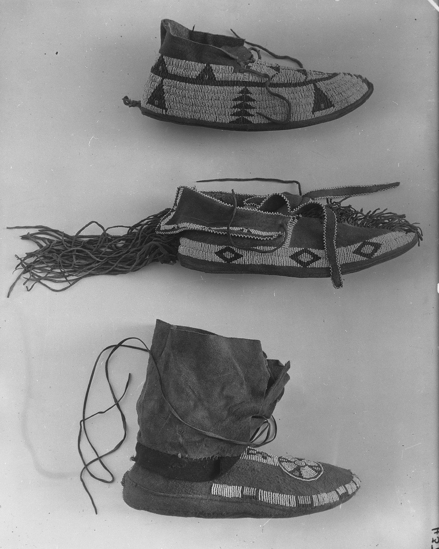 Hearst Museum object titled Moccasins, accession number 2-5516a,b, described as Pair. High ankle cuffs. Rosette and band geometrical design in blue/tan/white /pink beads.