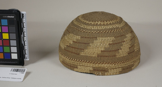 Hearst Museum object 2 of 2 titled Cap, accession number 1-1800, described as Cap basket; twined. Warp is Hazel (Corylus cornuta californica) weft is Sugar pine root (Pinus lambertiana). White pattern is Bear grass (Xerophyllum tenax). Red dye is Chain fern (Woodwardia spinulosa) in Alder (Alnus rubra). New. Design: enikiviti.