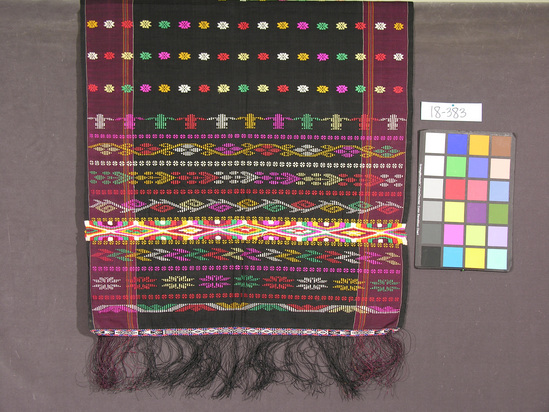 Hearst Museum object titled Shawl, accession number 18-383, described as Shawl; cotton âslendang;â warp stripe with multicolored embroidered designs on black, brown ground; narrow ends fringed. Worn by female guests at weddings. Worn over right shoulder. 69.5 x 204 cm including fringe.