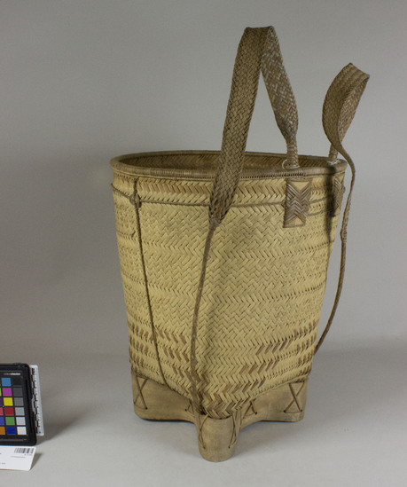 Hearst Museum object titled Basket, backpack, accession number 9-17153, described as Backpack basket. Deep and wide; flat, square bottom; plaited weave; base made of bent wood in “X” pattern. Carrying straps are woven flat pieces which become narrow like rope and are strung through the base. Basket is reinforced and decorated by additional twining around entire outside of basket.