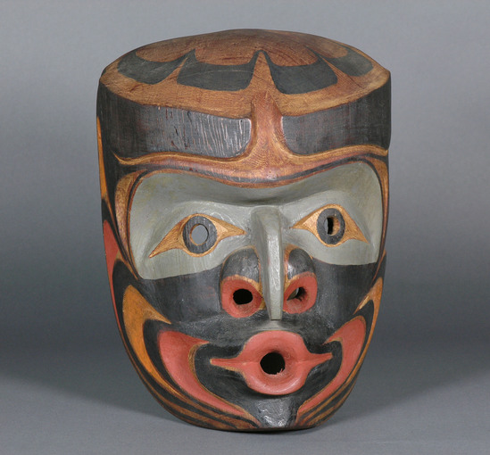 Hearst Museum object 1 of 3 titled Mask, accession number 2-66925, described as Wood, red cedar, anthropomorphic, polychrome in natural, red, grey and brown. Beaked nose, prominent nostrils, lips pursed for whistling/singing, eyes (black rimmed circular holes) under heavy black eyebrows. Equipped with 2 small eyebolts and wire. Back inscribed, "Chiefs Mask" "Jack James, Gilford Isle, B.C." Commercial paint.